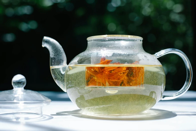 a glass tea pot sitting on top of a table, inspired by Ma Yuan, unsplash, white and orange, al fresco, green tea, uncropped