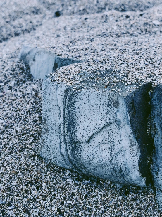 a large rock sitting on top of a sandy beach, an album cover, inspired by Vija Celmins, unsplash, concrete art, blue gray, cubic minerals, black lung detail, detailed product image