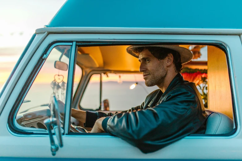 a man sitting in the driver's seat of a blue van, a portrait, by Lee Loughridge, unsplash contest winner, golden hour in pismo california, straw hat and overcoat, eric bana, extremely handsome