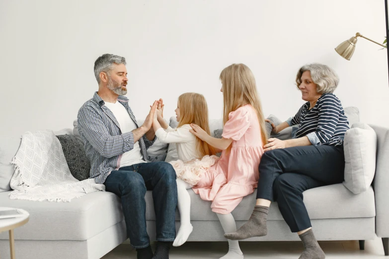 a group of people sitting on top of a couch, holding hands, families playing, profile image, high - quality photograph