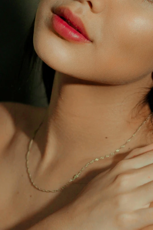 a close up of a woman wearing a necklace, an album cover, inspired by Elsa Bleda, trending on pexels, asian female, gold dappled light, olive, curved body