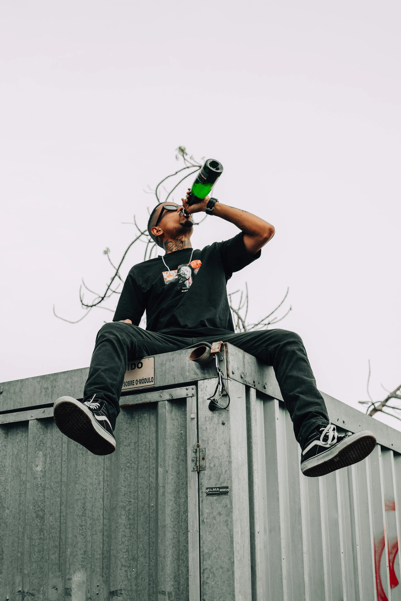 a man sitting on top of a metal container, trending on pexels, monster energy drink, lil uzi vert, drinking whiskey, high above the ground