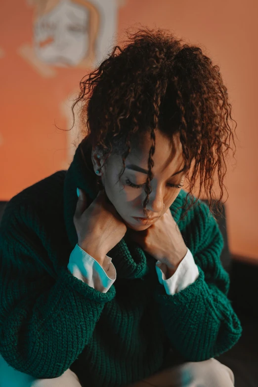 a woman sitting on a couch with her hand on her chin, an album cover, trending on pexels, antipodeans, ashteroth, wearing a green sweater, sad look, teal