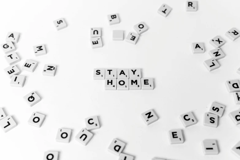 the word stay home spelled in scrabbles on a white surface, a black and white photo, by Nicolette Macnamara, pixabay, ascii art, set pieces, alex yanes, environmental, you may say i'm a dreamer
