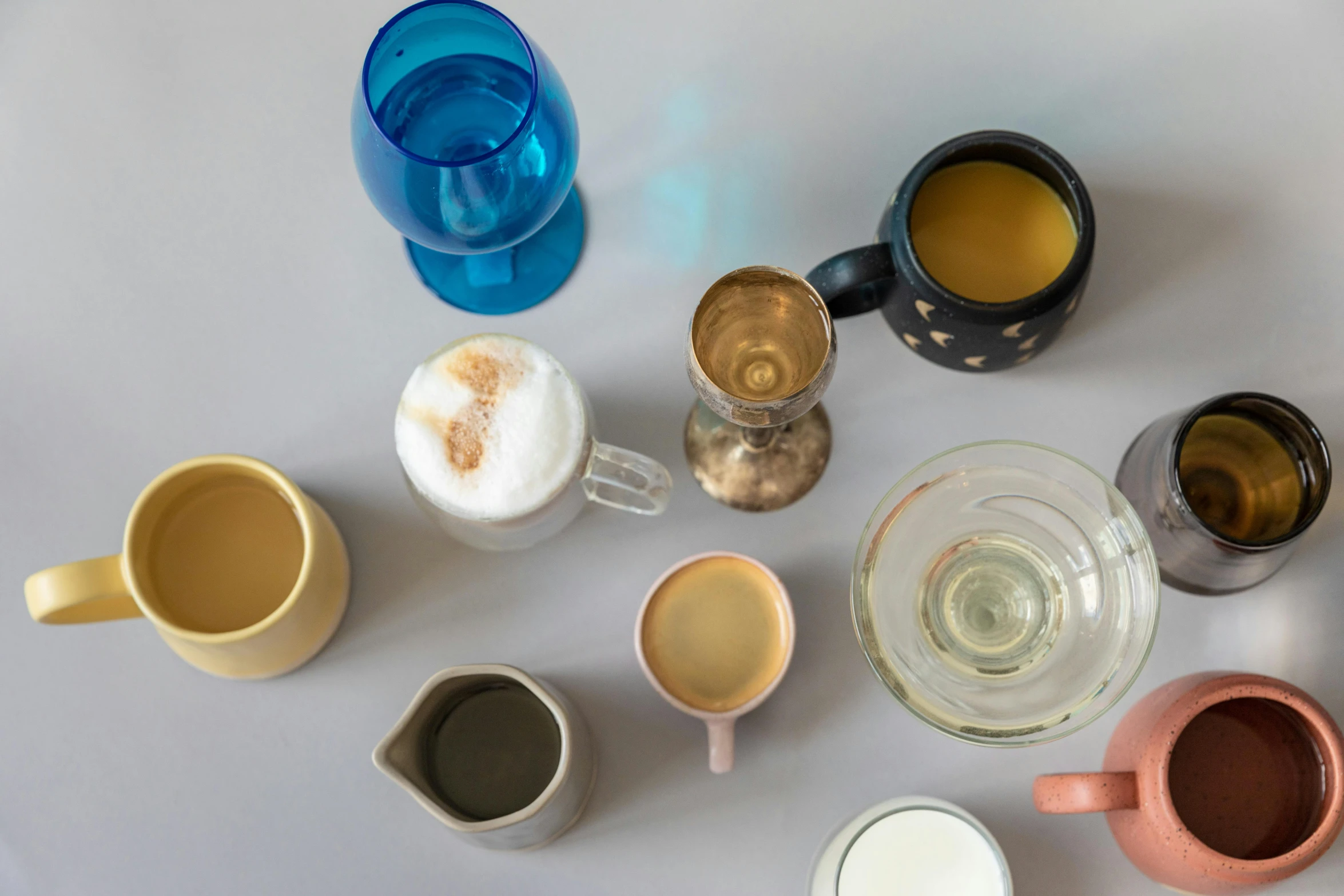 a number of cups of coffee on a table, a still life, by Jessie Algie, trending on unsplash, process art, colored milk tea, on grey background, glassware, dezeen showroom