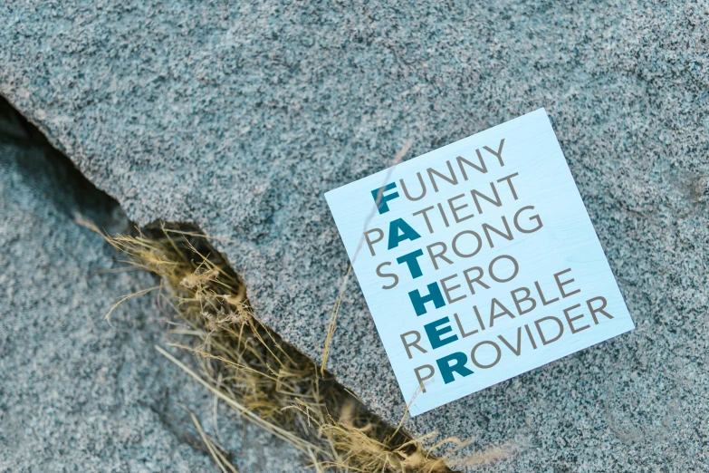 a sticker sitting on the side of a rock, father figure image, square, words, background image