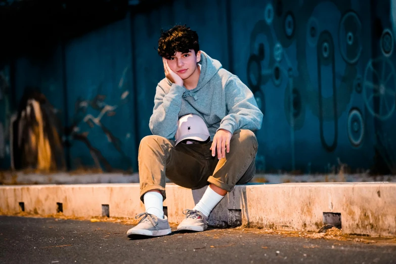 a young man sitting on a curb with a skateboard, unsplash, avatar image, wearing a light grey crown, declan mckenna, (night)