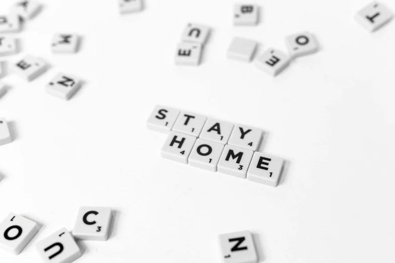 the word stay home spelled in scrabbles on a white surface, a black and white photo, by Matija Jama, pixabay, art-house aesthetic, background image, home display, key still