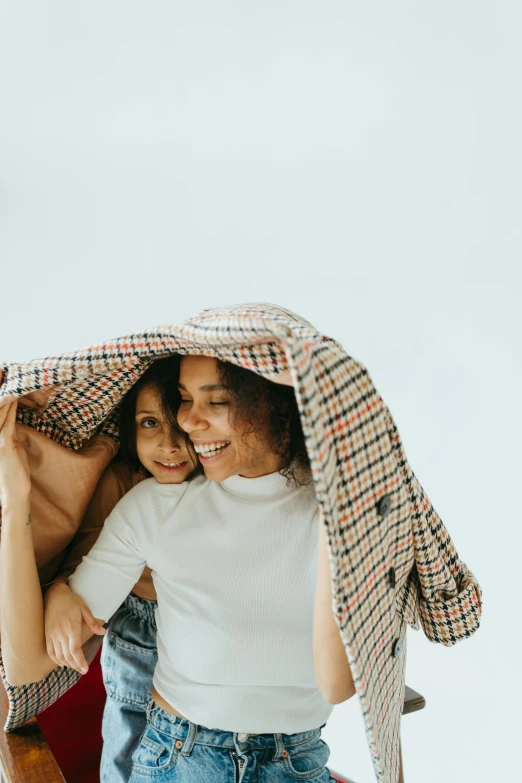 a man and a woman standing under a blanket, unsplash contest winner, minimalism, happy kid, woman holding another woman, turning her head and smiling, chequered cape