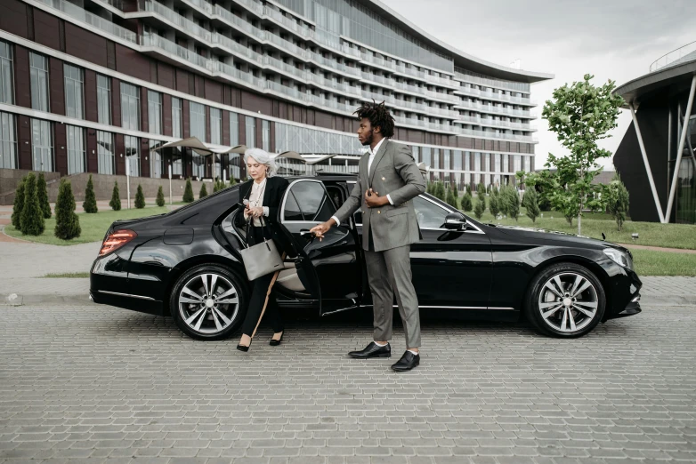 a man and a woman standing next to a car, black. airports, luxurious environment, bay area, thumbnail