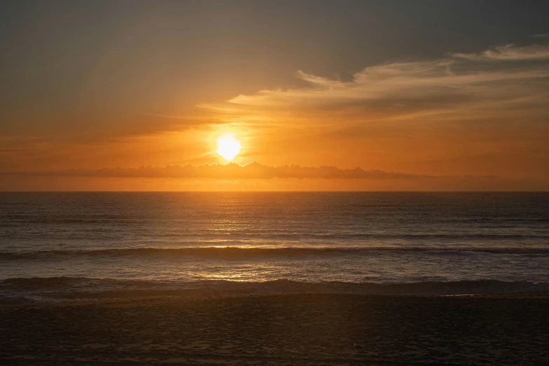 the sun is setting over the ocean on the beach, by Peter Churcher, pexels contest winner, golden bay new zealand, high quality photo, in a sunset haze, overlooking the ocean