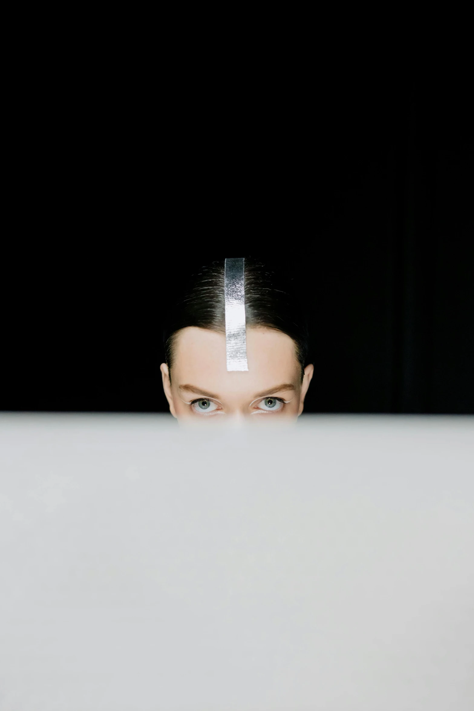 a woman sitting in front of a laptop computer, inspired by Marina Abramović, unsplash, purism, symmetry!! portrait of cyborg, hiding behind obstacles, large forehead, photographed for reuters