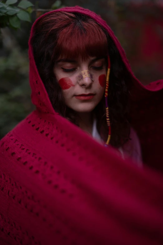 a woman in a red cloak with red paint on her face, an album cover, inspired by Elsa Bleda, pexels contest winner, cottagecore hippie, red hood cosplay, melanie martinez, red bandana