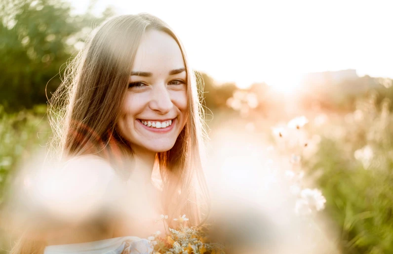 a woman holding a bunch of flowers in a field, pexels contest winner, backlit beautiful face, sydney sweeney, large smile, avatar image