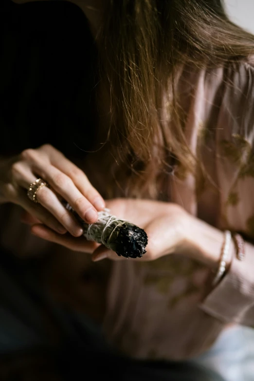 a close up of a person holding a cigarette, inspired by Elsa Bleda, large obsidian crystals, herbs, hands in her hair, silver and muted colors