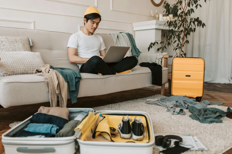 a man sitting on a couch with a laptop, pexels contest winner, maximalism, in suitcase, yellow clothes, aussie, inspect in inventory image