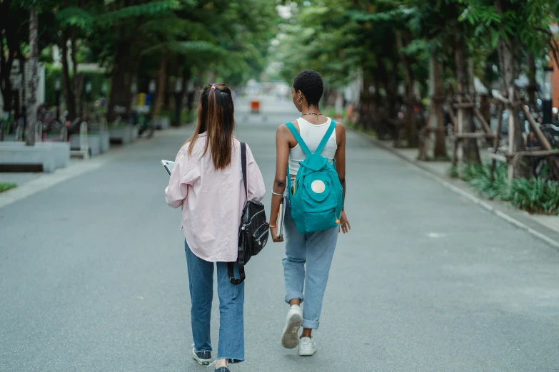 a couple of women walking down a street, trending on pexels, at college, a green, background image, student