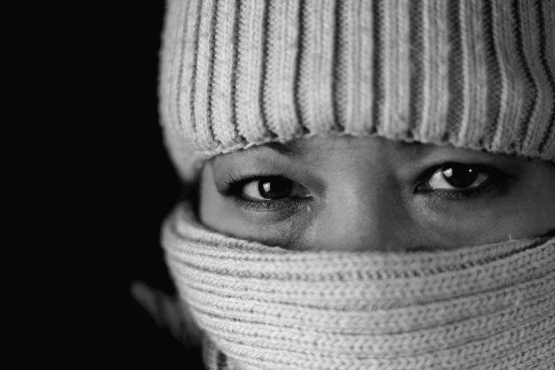 a close up of a person wearing a hat and scarf, a black and white photo, pexels, balaclava covering face, detailed face of a asian girl, frosty white eyes, from waist up