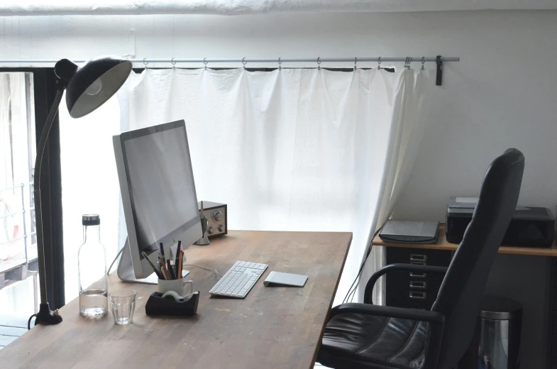 a computer sitting on top of a wooden desk, inspired by Masamitsu Ōta, light and space, white wall coloured workshop, curtains, studio lights, neat and tidy