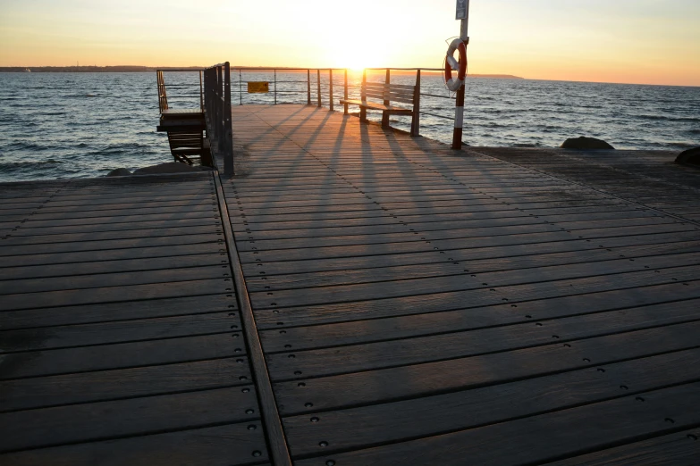 a bench sitting on top of a wooden pier next to the ocean, in the sunset, manly, wooden bridge, sunshafts