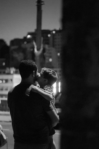 a couple of people that are standing in the street, a black and white photo, by Alexis Grimou, two men hugging, summer night, 15081959 21121991 01012000 4k, in a square