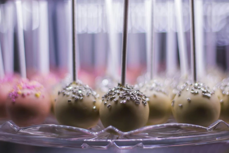 a tray of cake pops sitting on top of a table, by Emma Andijewska, unsplash, renaissance, intricate sparkling atmosphere, profile image, background image, fan favorite