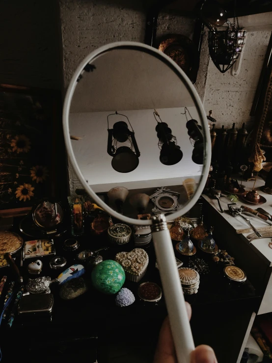 a person holding a magnifying mirror in their hand, pexels contest winner, hyperrealism, displayed on an altar, cluttered room, low quality photo, - 9