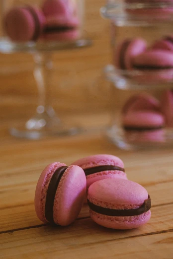 a pile of pink macarons sitting on top of a wooden table, inspired by François Girardon, renaissance, black forest, medium-shot, drink, zoomed in