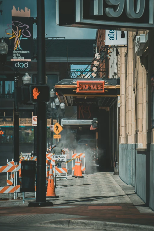 a street sign sitting on the side of a road, by Andrew Domachowski, pexels contest winner, buildings covered with greebles, scaffolding, modern chicago streets, rising steam