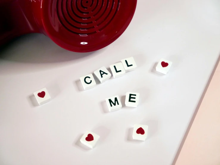 a red mug sitting on top of a white counter, inspired by Cerith Wyn Evans, letterism, milk cubes, telephone, red hearts, detail shot