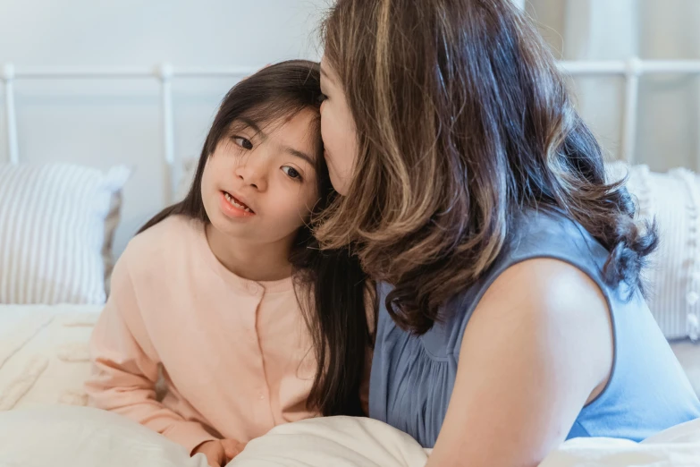 a woman sitting on top of a bed next to a little girl, trending on pexels, mingei, asian face, whispers, educational, girl with brown hair