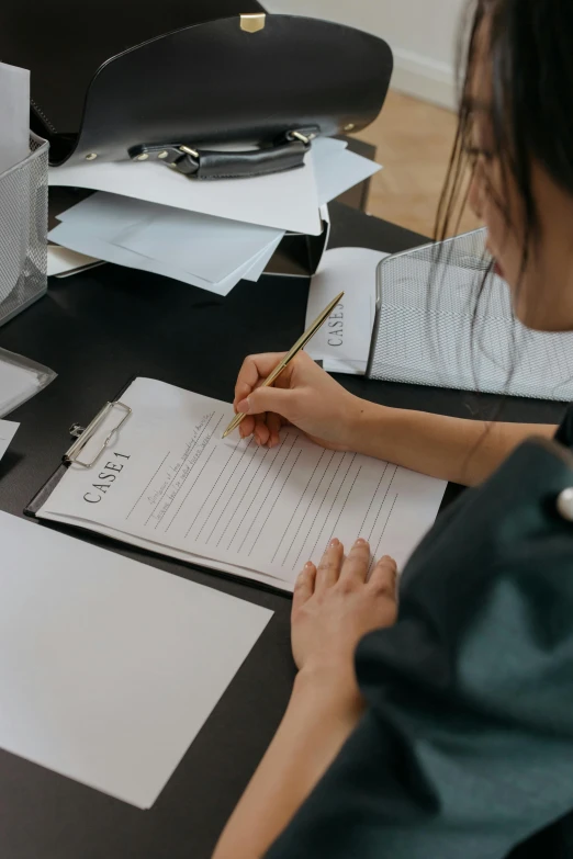 a woman sitting at a desk writing on a piece of paper, documentation, pokimane, low quality photo, designer product