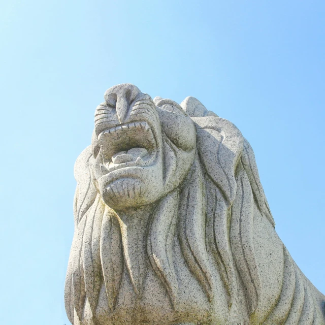 a stone statue of a lion against a blue sky, by Niko Henrichon, pexels contest winner, singapore, growling, parapets, lion icon