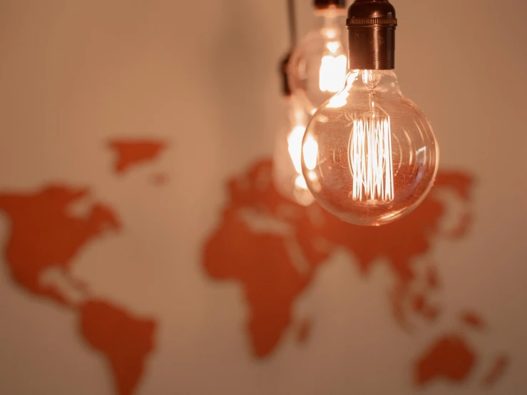 a close up of a light bulb with a world map in the background, trending on pexels, torches on the wall, warm coloured, bright thin wires, reddish lighting