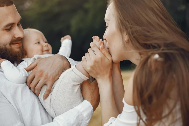 a man holding a baby in his arms, pexels contest winner, hand over mouth, happy family, looking at the ground, cute woman