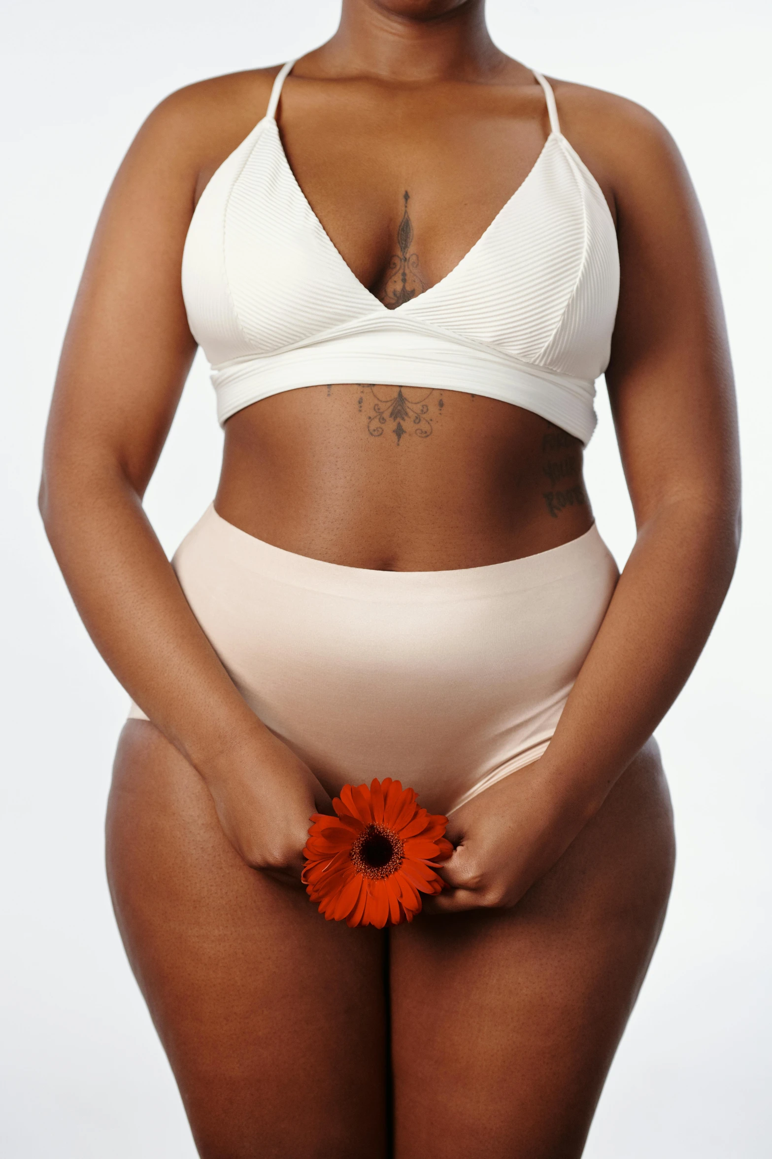 a woman in a bikini holding a flower, bra and shorts streetwear, rubenesque, creamy, unbothered