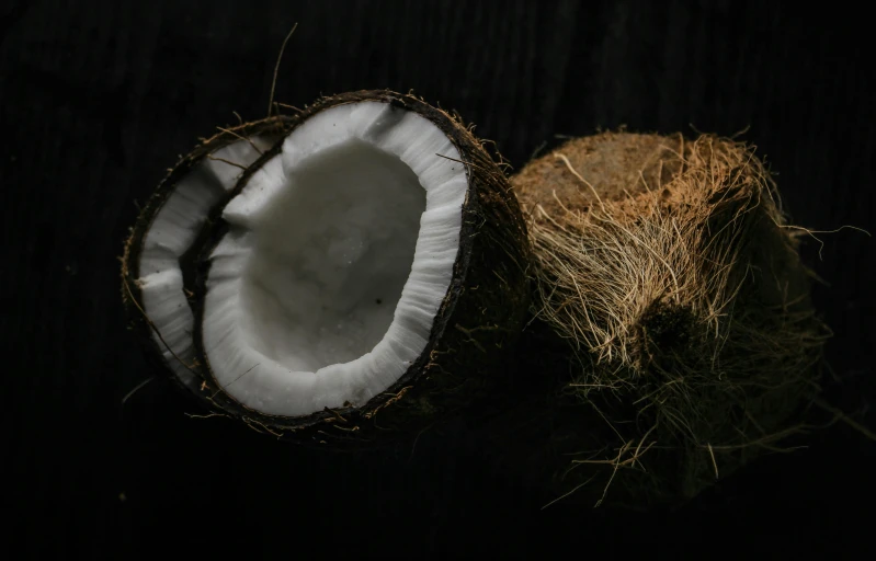 a half eaten coconut sitting on top of a wooden table, unsplash, hurufiyya, on a black background, male and female, stacked image, thumbnail