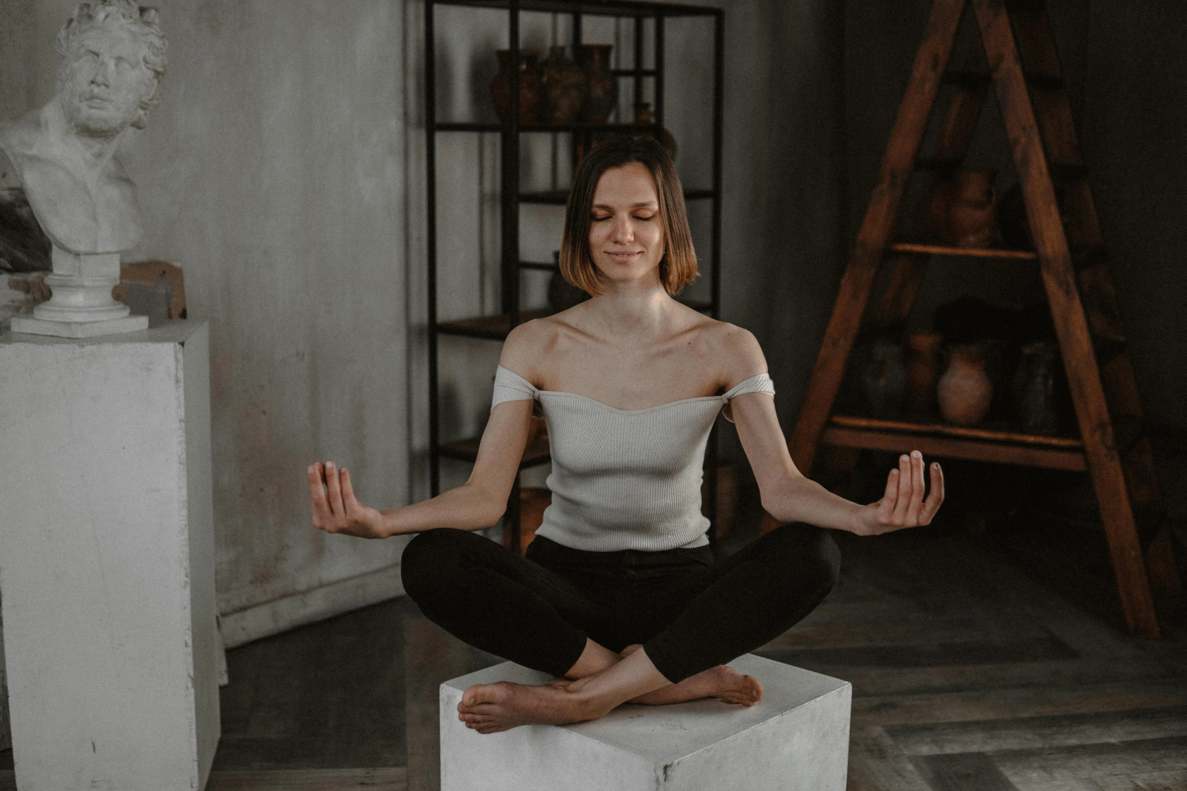 a woman sitting in the middle of a meditation pose, a statue, trending on pexels, massurrealism, pretty face with arms and legs, statue of a cubes and rings, satisfied pose, grey