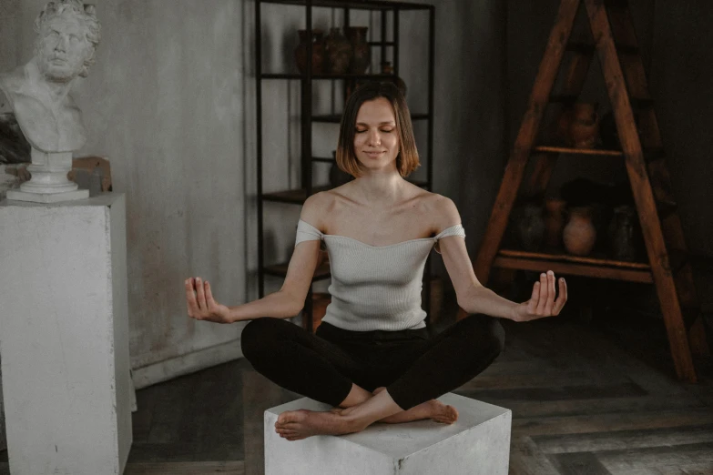 a woman sitting in the middle of a meditation pose, a statue, trending on pexels, massurrealism, pretty face with arms and legs, statue of a cubes and rings, satisfied pose, grey