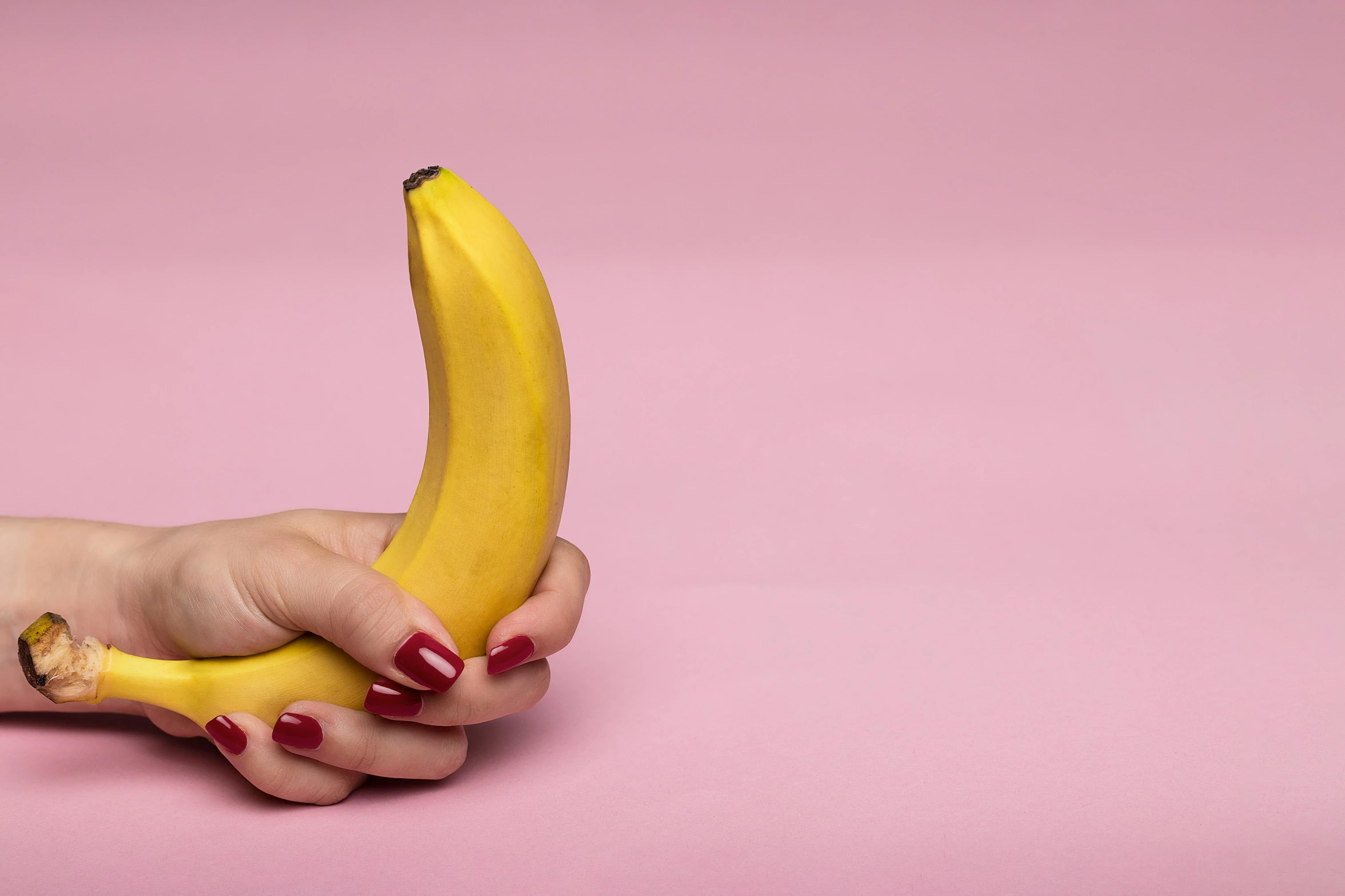 a woman's hand holding a banana on a pink background, trending on pexels, adult video store, lesbians, vibrating, 4 0 years old man