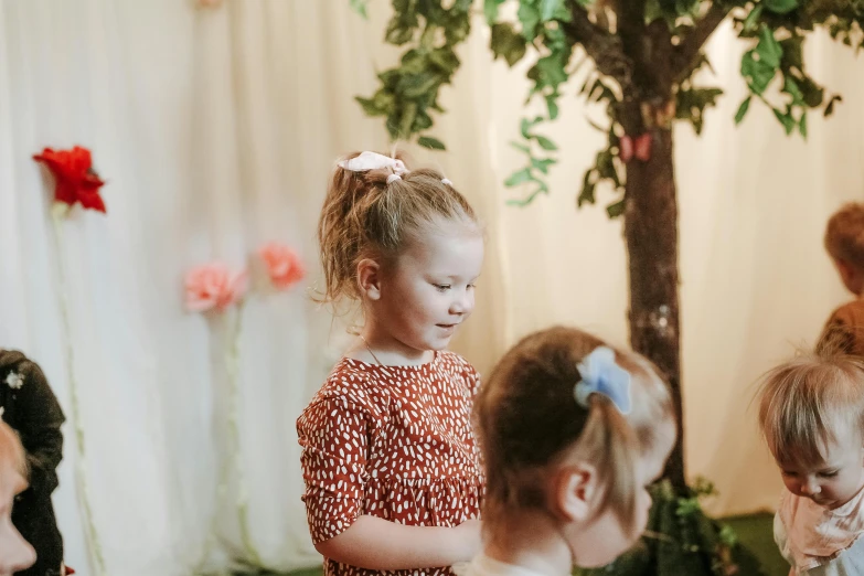 a group of little girls standing next to each other, by Emma Andijewska, pexels contest winner, interactive art, decoration around the room, tree in the background, two pigtails hairstyle, event photography