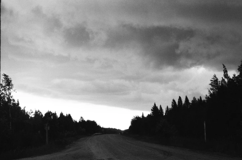 a black and white photo of a dirt road, by Maurycy Gottlieb, dark night stormcloud, taiga landscape, album cover, taken in the early 1990s