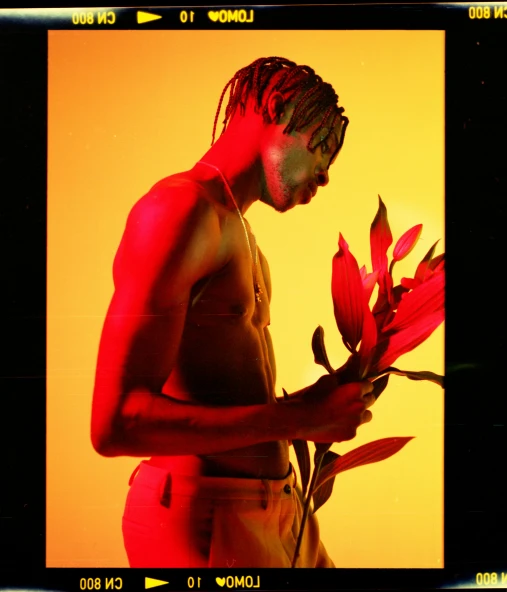 a man holding a flower in front of a yellow background, an album cover, by Cosmo Alexander, trending on pexels, realism, high red lights, man is with black skin, back light, palms
