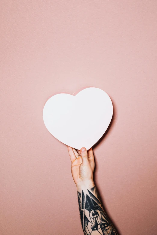 a person holding a paper heart in their hand, an album cover, by Julia Pishtar, trending on pexels, pastel pink skin tone, 144x144 canvas, tattooed, people