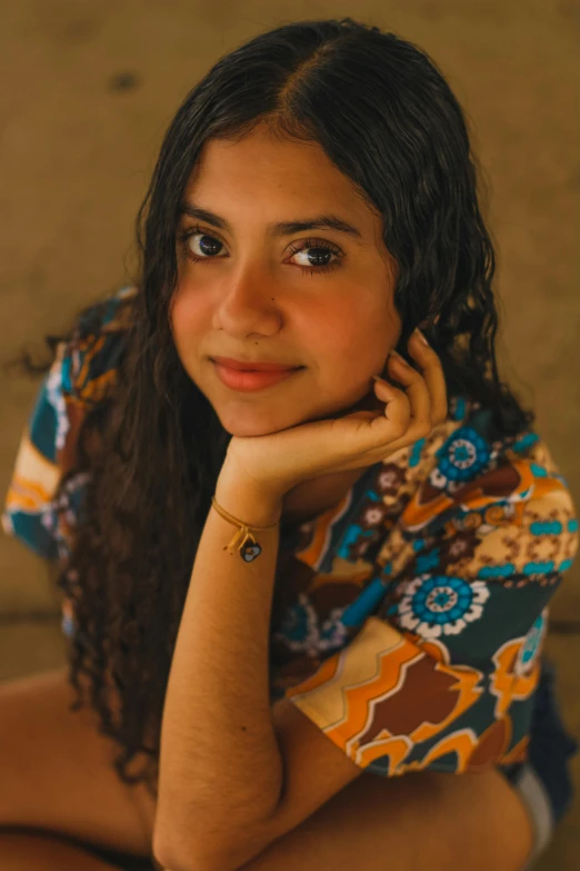 a woman sitting on the ground with her hand on her chin, an album cover, by Olivia Peguero, trending on pexels, renaissance, young middle eastern woman, cottagecore hippie, lovingly looking at camera, black teenage girl