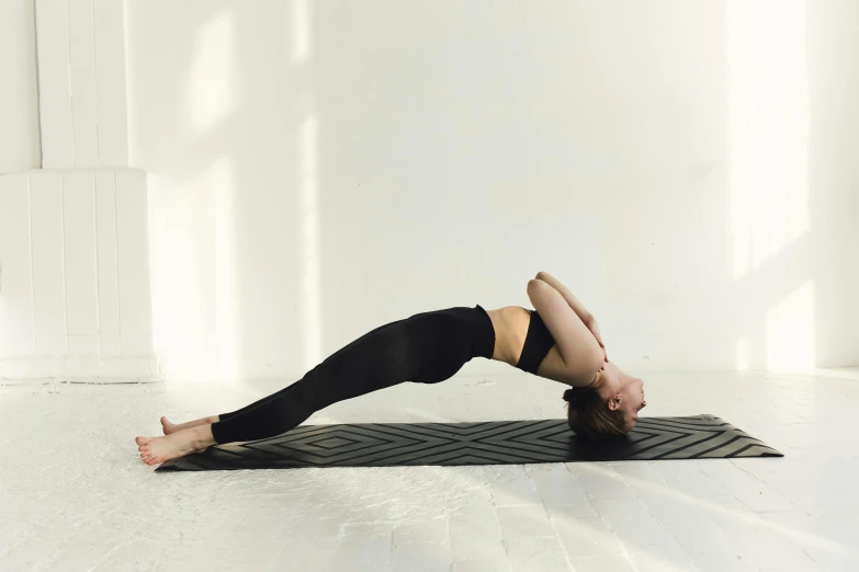 a woman doing a yoga pose on a mat, trending on pexels, arabesque, wearing black tight clothing, silicone skin, profile image, thumbnail