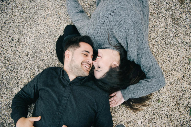 a man and a woman laying on the ground, by Lucia Peka, trending on pexels, smiling couple, head straight down, romantic lead, 1 2 9 7