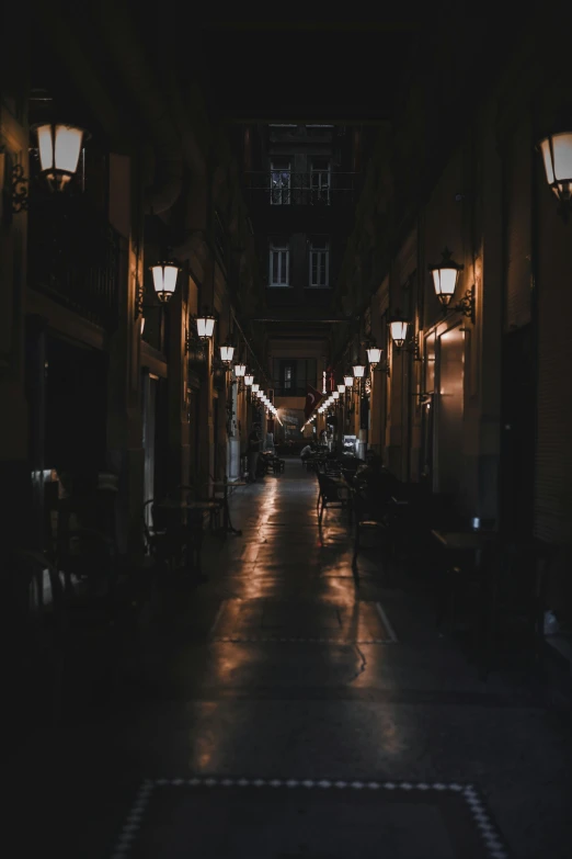 a street filled with lots of lights next to tall buildings, a picture, unsplash contest winner, baroque, dark hallways, spanish, deserted, gas lamps