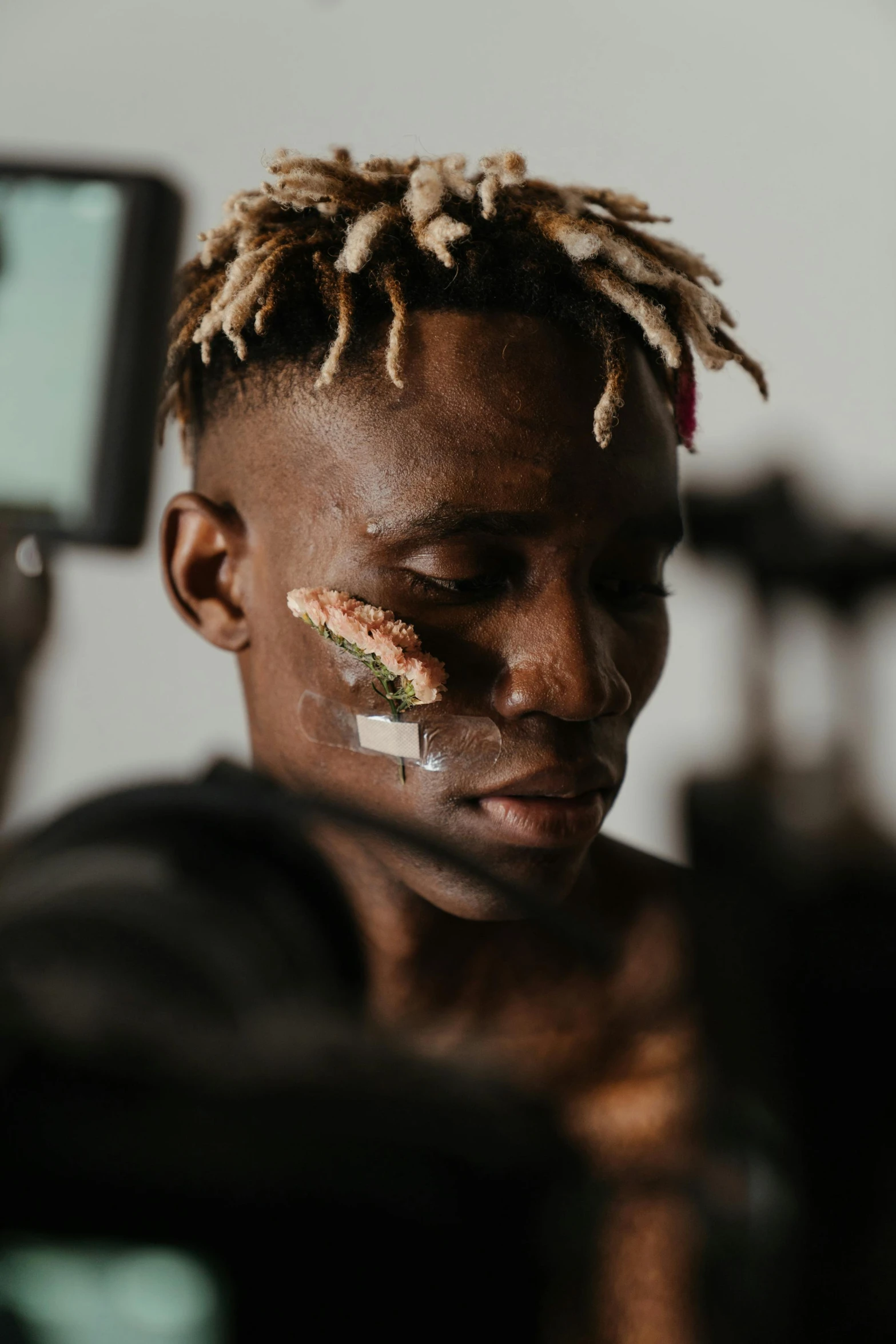 a man with a piece of food on his face, trending on pexels, afrofuturism, undercut hairstyle, in a workshop, young thug, cracked body full of scars