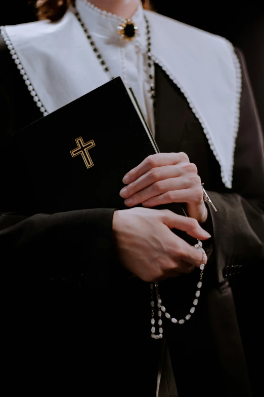 a woman holding a rosary and a bible, an album cover, by Sebastian Vrancx, trending on unsplash, nun outfit, 15081959 21121991 01012000 4k, a man wearing a black jacket, controversial